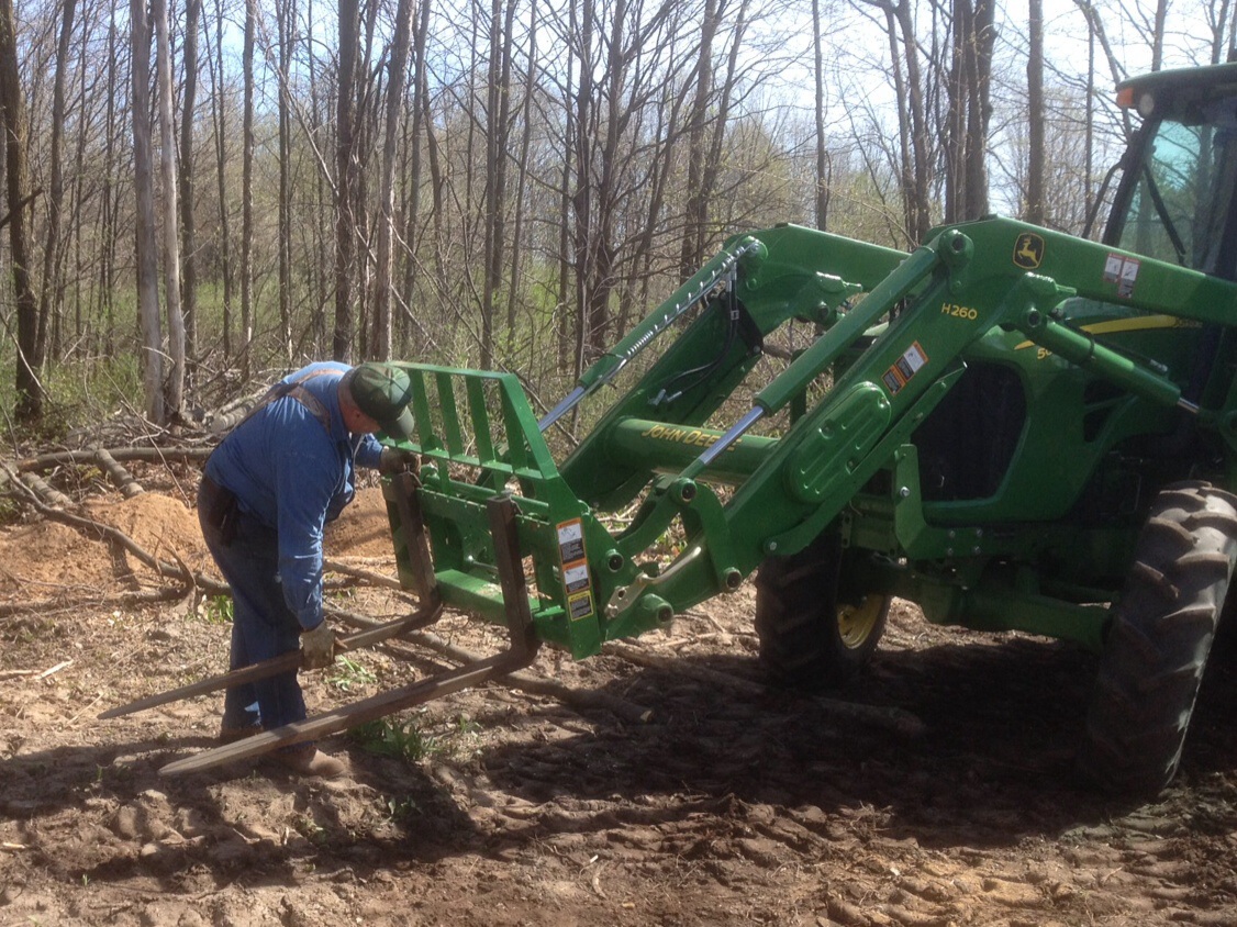 A club member prepping the tractor to move stumps and heavier trunk sections.